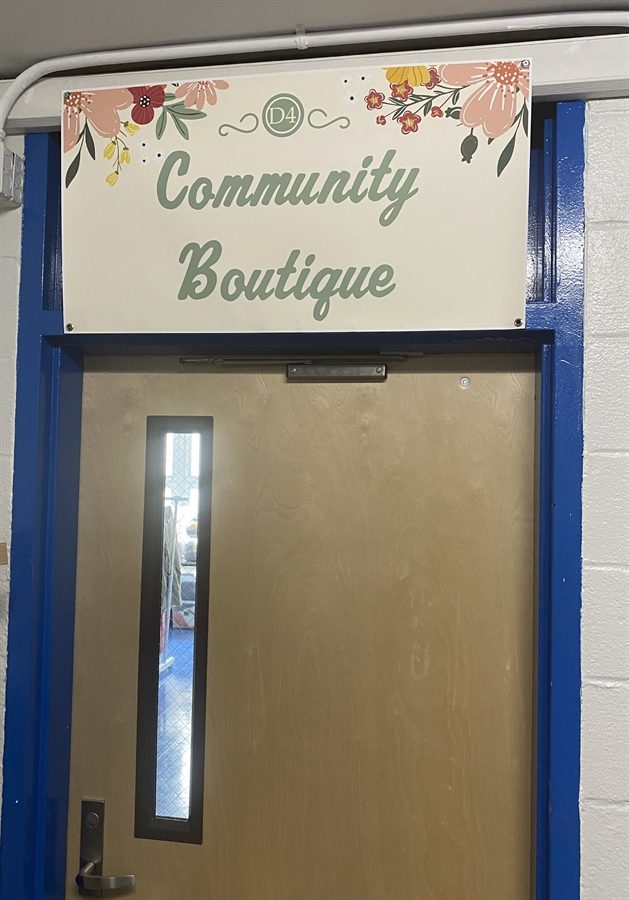 A door with a floral sign reading Community Boutique
